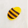 A yellow plush dog chew toy shaped like a slipper with black stripes.