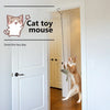 A tabby cat is playing with a hanging mouse toy inside a white door frame.