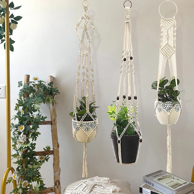 A collection of macrame plant hangers and a wooden ladder decorated with greenery on a white wall.