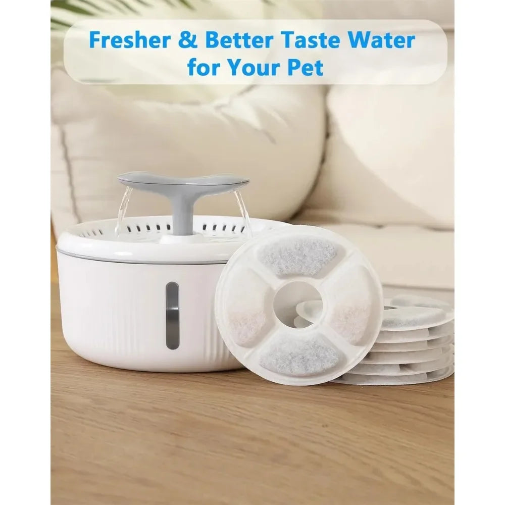 A white water fountain with a gray spout and replacement activated carbon filters is shown on a wooden surface.