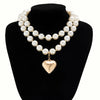 A choker necklace featuring multiple strands of white pearls culminating in a gold heart pendant.