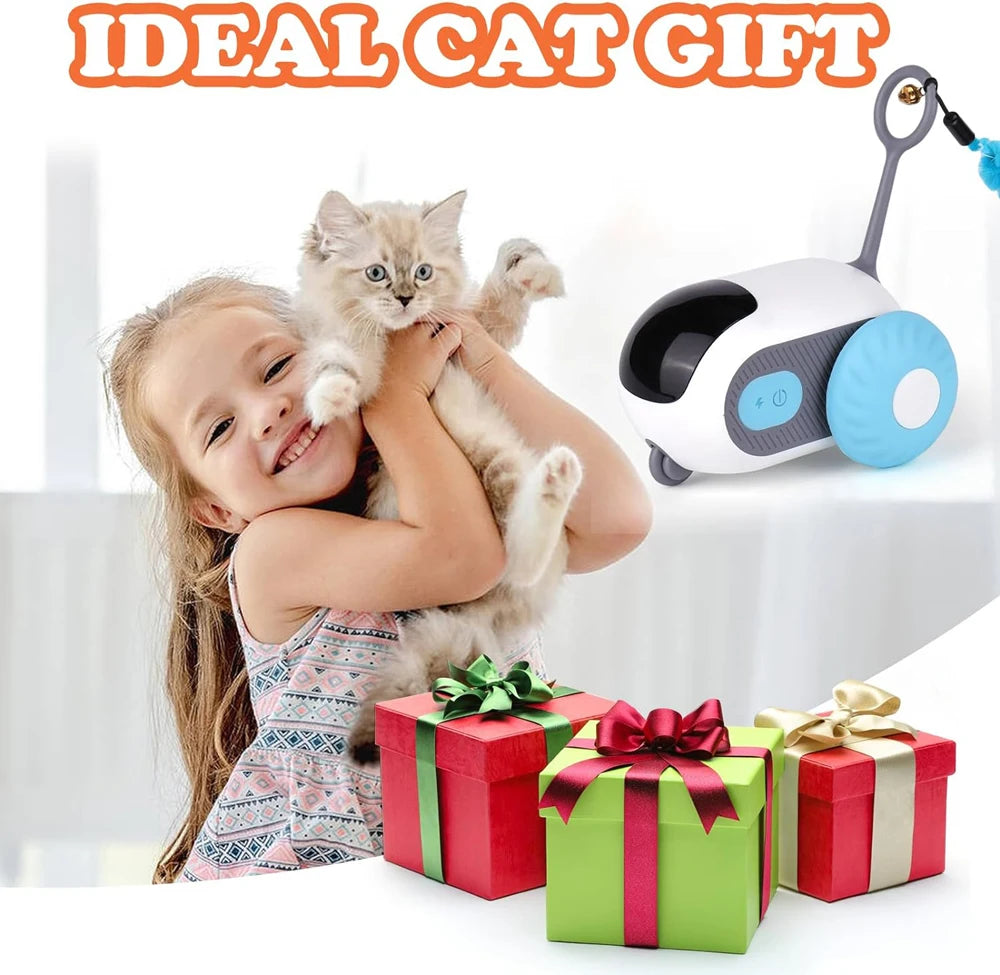 A young girl is smiling while holding a kitten, with an automatic pet toy car for cats and dogs visible in the background.