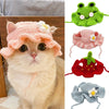 A fluffy ginger cat wearing a pink knitted flower hat and several other knitted pet hats.