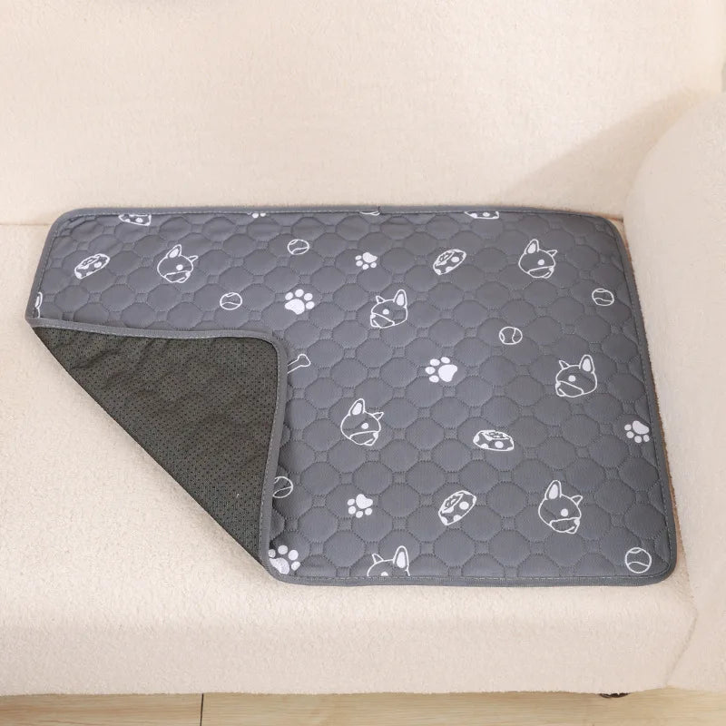 A gray reusable washable pet training mat with a repeating pattern of white paw prints and pet silhouettes is placed on a lig