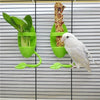 A white bird is feeding from a green shuttlecock style cuttlebone stand with sunflower seeds.