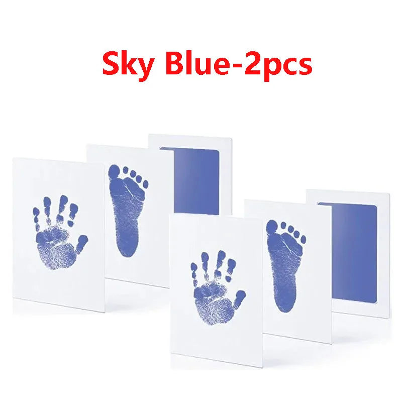 Two white cards showing blue handprints and footprints for baby keepsakes