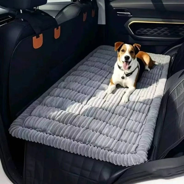 A dog is lying on a gray plaid flannel pet seat protector and car mat inside a dark car seat.