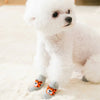 A white Pomeranian dog wearing anti-slip knit socks with an orange tiger design.