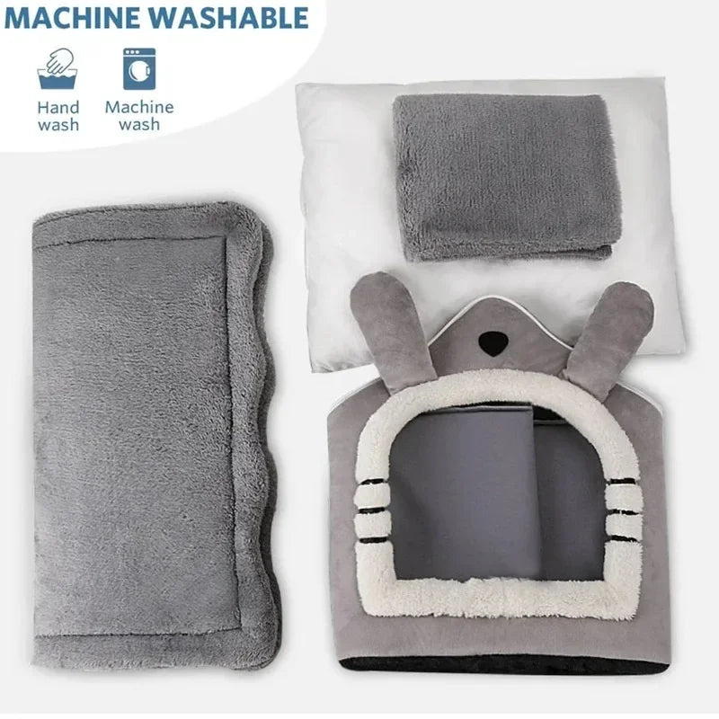 A gray removable dog house pet bed with a rabbit-like face design shown next to a rectangular gray pet mat.