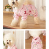 A fluffy white dog wearing pink patterned cotton pajamas.