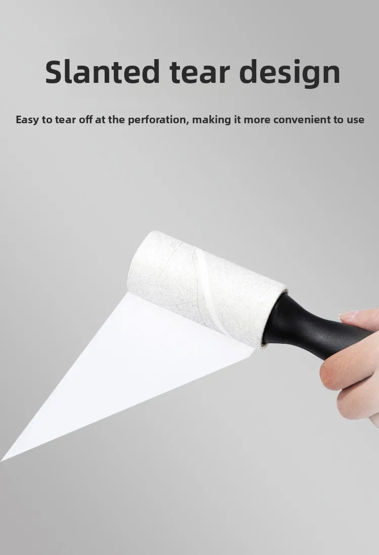 A hand is holding a slanted tear design lint roller, showing the white roller material and black handle.