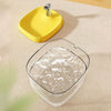 A yellow cat drinking fountain with a metal spout is shown on a light-colored surface.