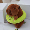 A brown capybara plush doll wearing a lime green hoodie and wings, sitting on a white surface.