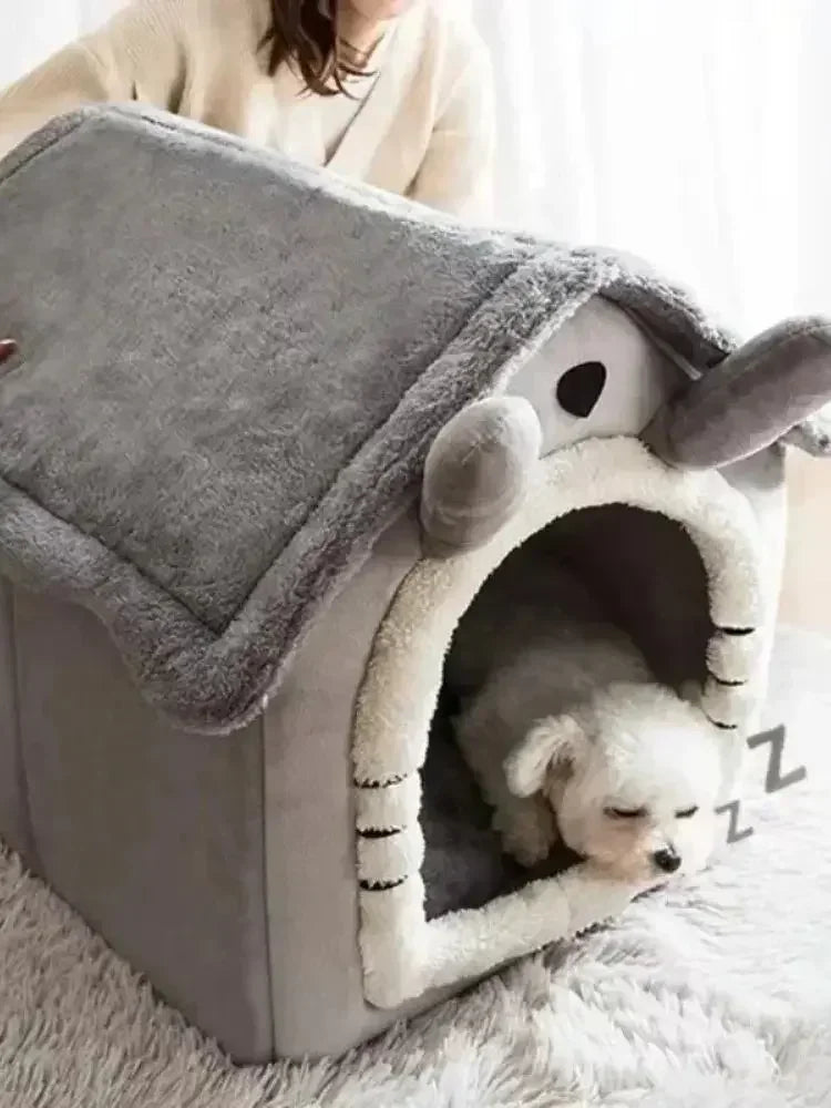 A gray pet house with a round entrance and soft lining, positioned on a white fluffy surface.