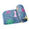 A rolled blue dog blanket featuring pink and yellow paw prints and a pink bone.