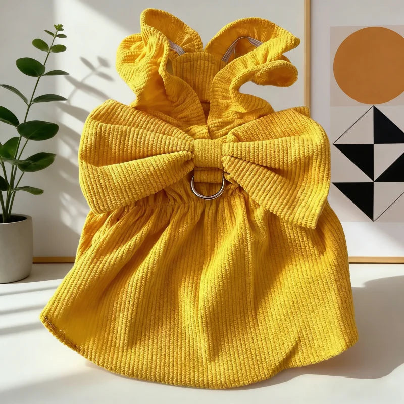 A bright yellow vintage corduroy pet dress featuring a bow and ruffle skirt, displayed on a white surface.