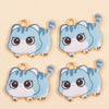 Two light blue cat pendant charms with white accents and gold-colored jump rings.