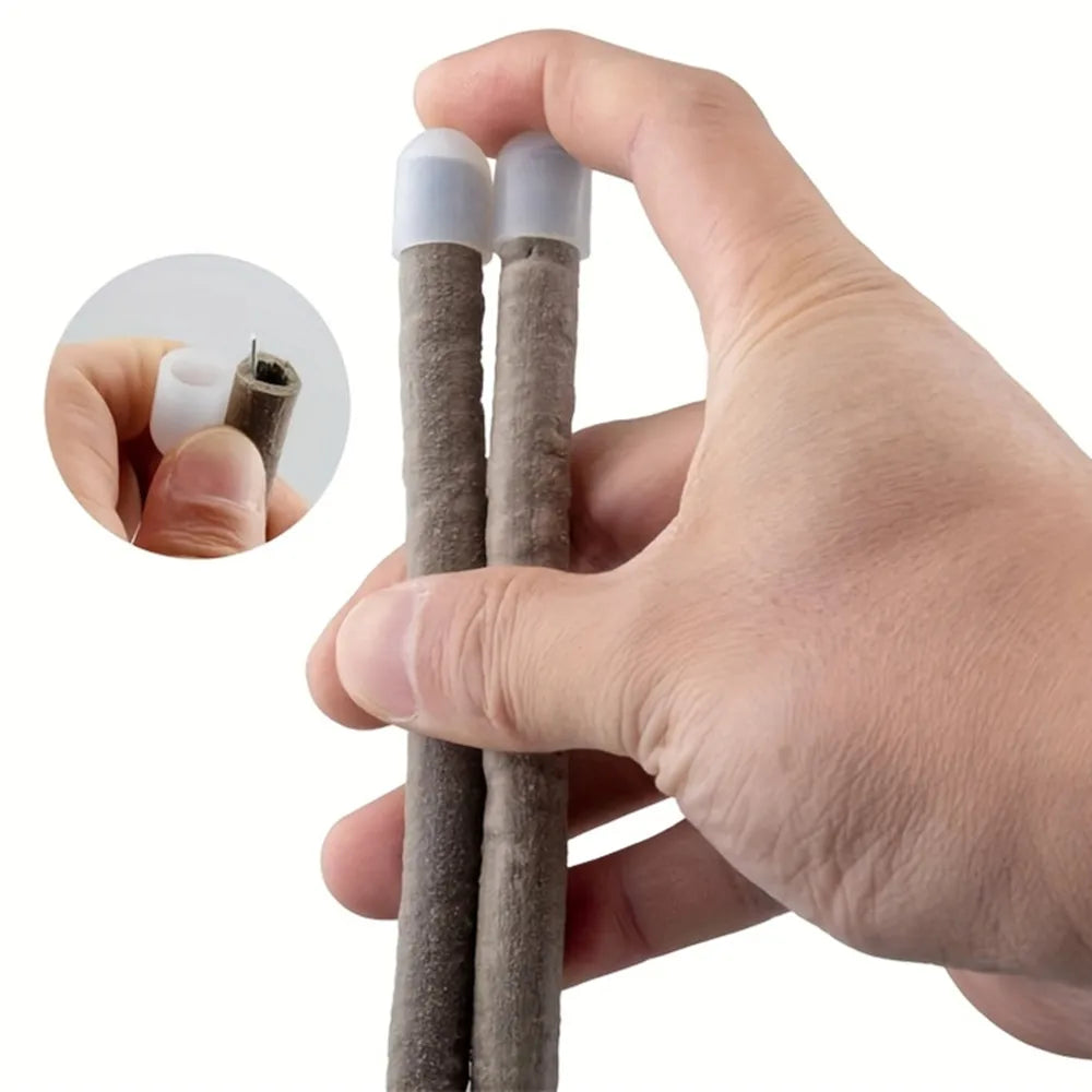 A hand holds two realistic artificial reptile vines with white tips for terrarium decor.