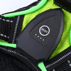 Close-up of a black LED dog harness with bright lime green reflective strips and an on/off switch.