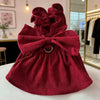 A deep red corduroy pet dress featuring a bow and ruffled skirt, displayed on a white surface.