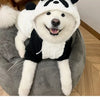 A white and black panda-themed fleece winter dog hooded coat displayed on a gray surface.