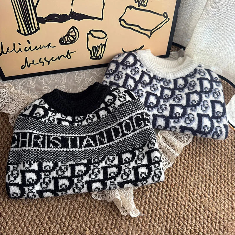 A black and white knit sweater featuring a repeating dog motif is displayed next to a cardboard box.