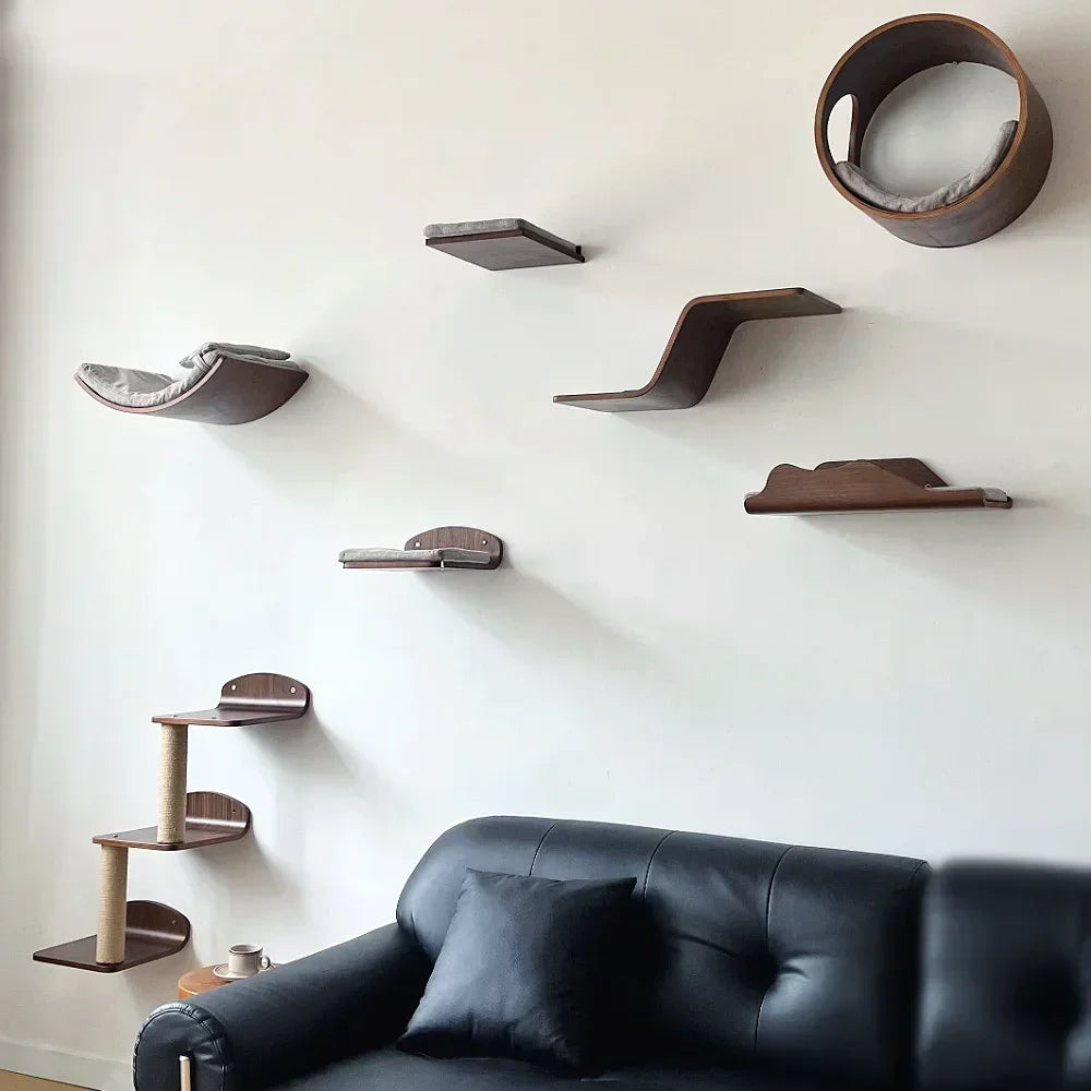 Wall-mounted cat tree with scratching stairs and hammock mounted on a white wall above a black leather sofa.