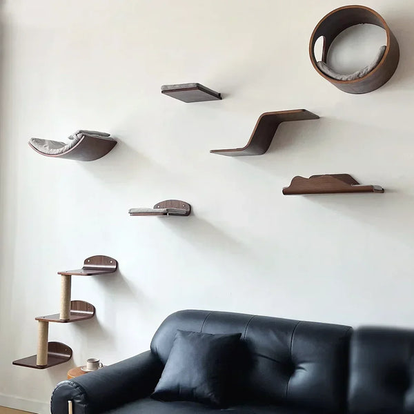 Wall-mounted cat tree with scratching stairs and hammock mounted on a white wall above a black leather sofa.