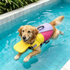 A golden retriever wearing a yellow life jacket is swimming in a blue pool.