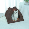 A brown foldable pet tent for cats is shown resting on a white fluffy surface.