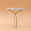 A light beige manual lint remover brush with a flat, ribbed head is shown against a plain background.