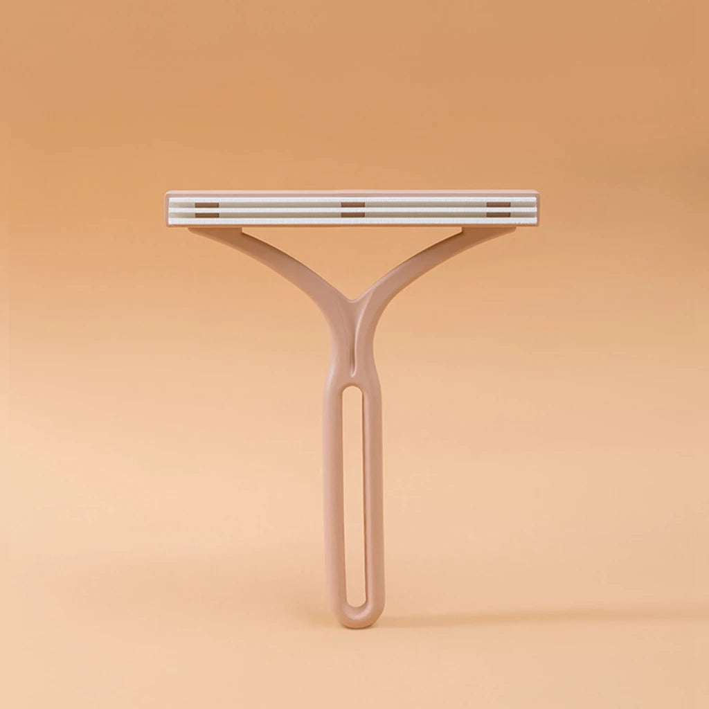 A light beige manual lint remover brush with a flat, ribbed head is shown against a plain background.