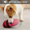 A dog is shown biting a pink striped plush toy designed to make a sound.