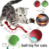 A striped kitten plays with a red and green interactive rolling ball toy for cats.