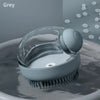 A grey pet bath brush with a clear dispenser is shown submerged in water.