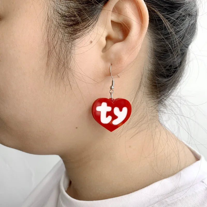 Red acrylic heart drop earrings with the initials ty dangling from silver ear wires.