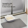 A white honeycomb cat litter mat placed on a gray mat in front of a window.
