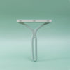 A white manual lint remover brush with a flat bar and a curved handle against a light green background.