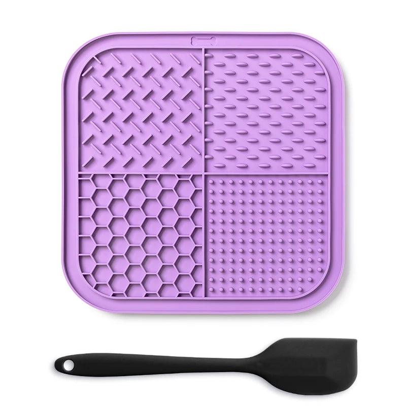 A purple silicone lick mat for dogs and cats with suction cups and a black spoon.