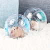 A small brown rodent is resting inside a clear, transparent pet exercise ball with blue accents on a white fluffy surface.