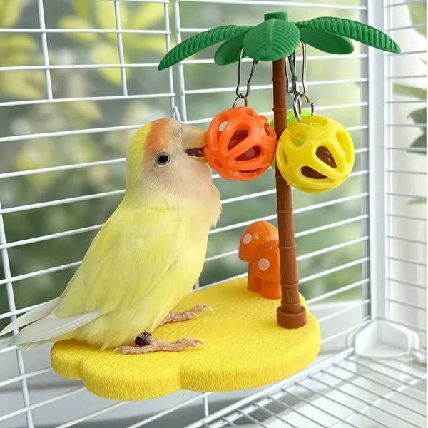 A yellow bird toy is perched on a tree branch with hanging orange and yellow play balls.