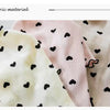 Nahaufnahme eines hellrosa Strickartikels mit schwarzen Herzmustern für Haustiere.