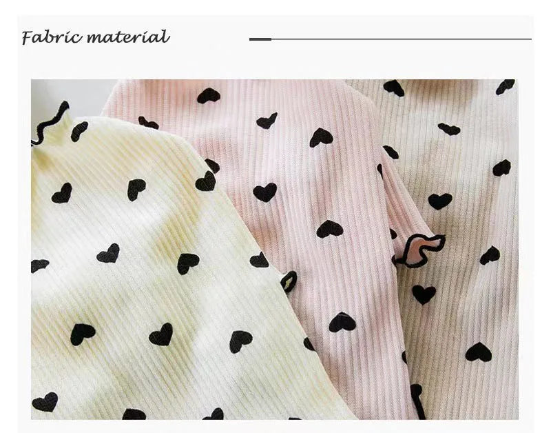 Nahaufnahme eines hellrosa Strickartikels mit schwarzen Herzmustern für Haustiere.