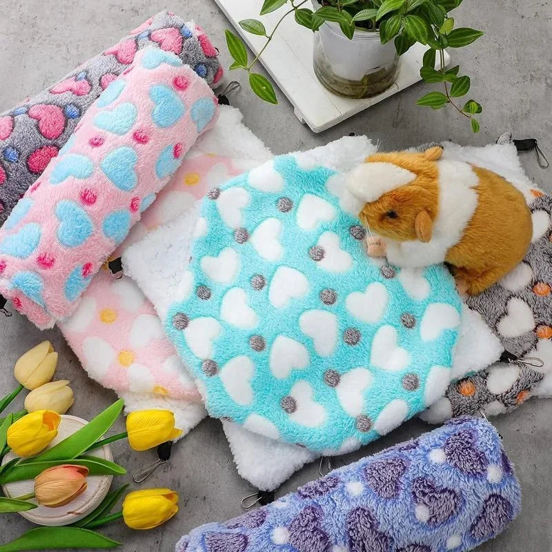 A collection of soft, colorful fleece hammocks for small pets, including pink, blue, and purple varieties.
