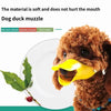 A brown dog wearing a yellow silicone muzzle on a white plate with a green leaf.