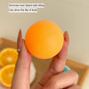 Eine Hand hält einen orangen, ballförmigen Spielzeug, das Spritzer verhindert und den Wurf von Essen auslöst.