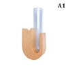 A wooden U-shaped holder for a glass tube, used as a pet whisker collector vase.