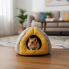 A cozy plush hanging nest shaped like a yellow and gray egg, containing a small brown rodent.