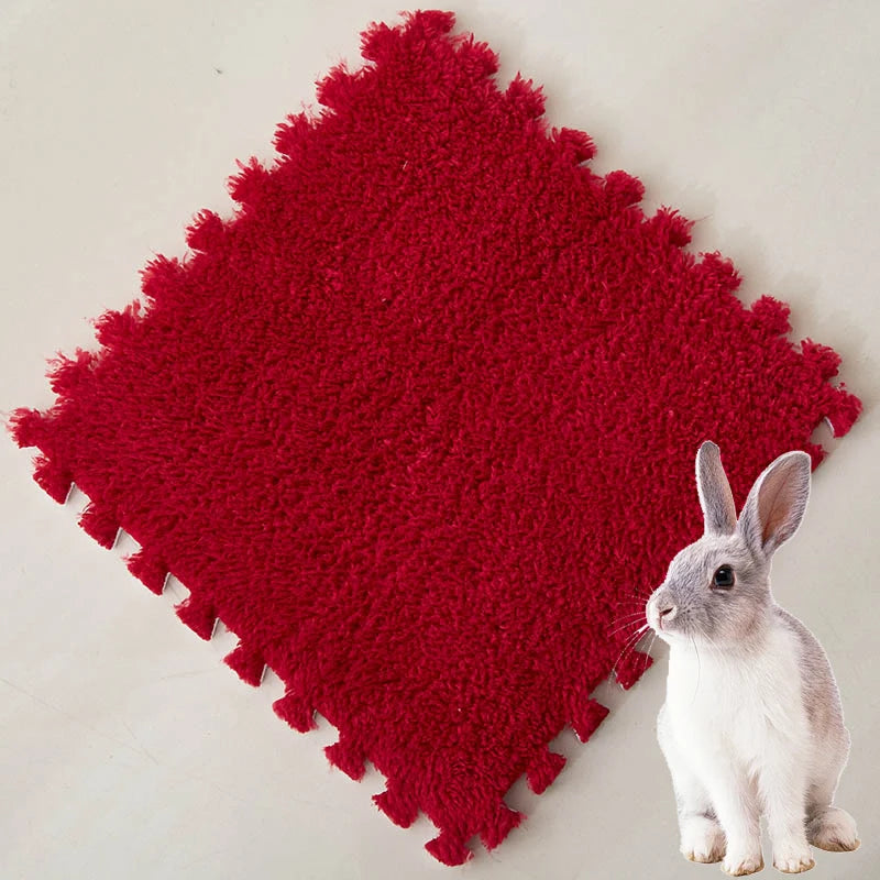 A bright red, textured fleece pet warming mat with a scalloped edge and a small gray rabbit sitting on it.
