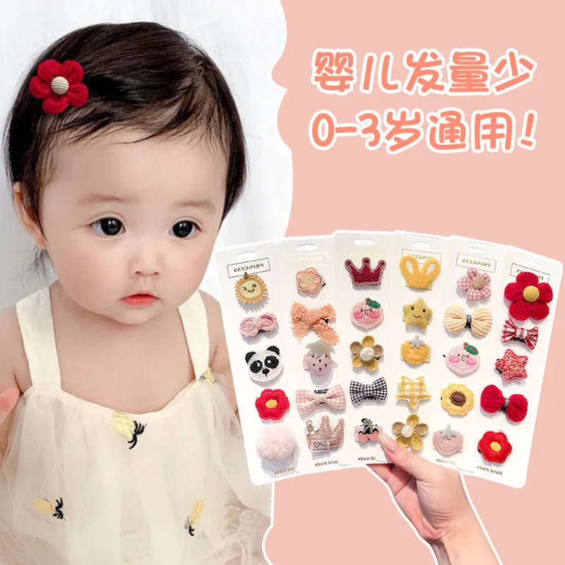 A hand holds a pack of five adorable flower-shaped baby hair clips for infants.